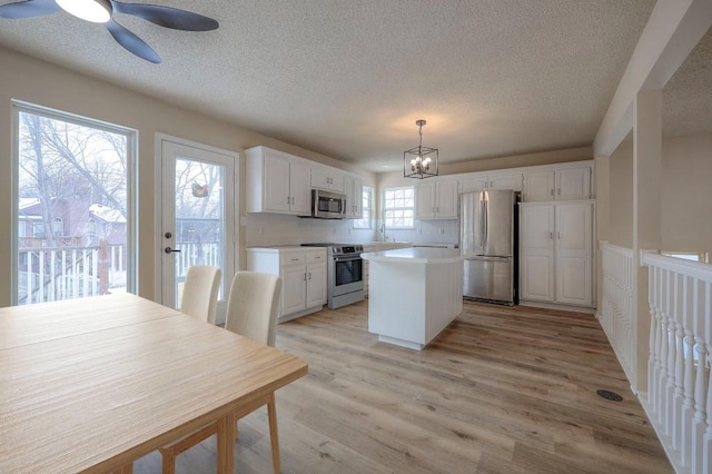 kitchen featuring stainless steel appliances, light countertops, white cabinetry, and pendant lighting