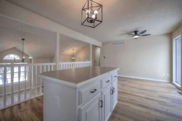 kitchen with visible vents, white cabinets, light countertops, and a center island