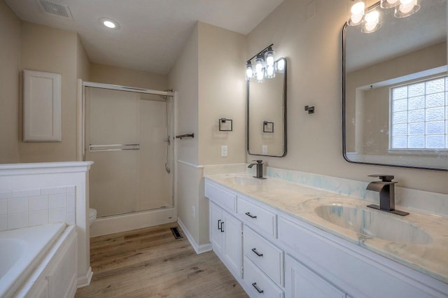 bathroom with toilet, wood finished floors, a sink, visible vents, and double vanity