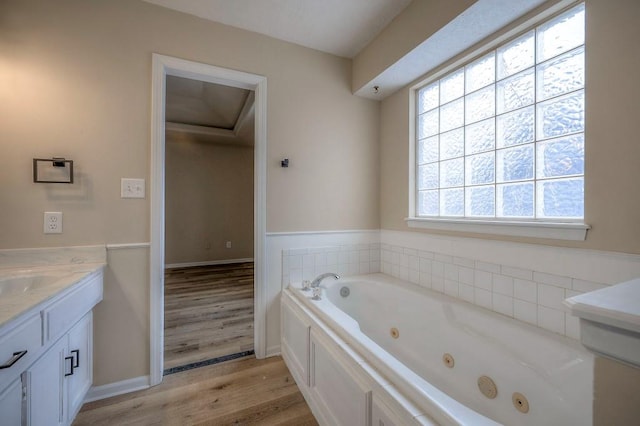 bathroom with a jetted tub, wood finished floors, vanity, and baseboards