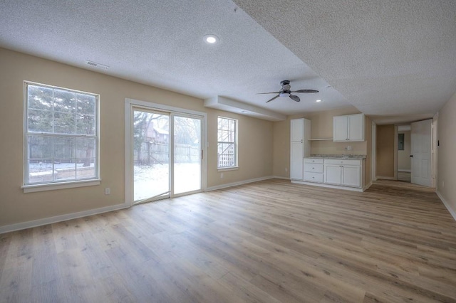 unfurnished living room with light wood-style flooring, baseboards, and a ceiling fan