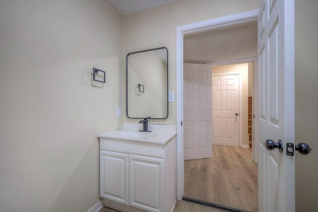 bathroom with baseboards, wood finished floors, and vanity