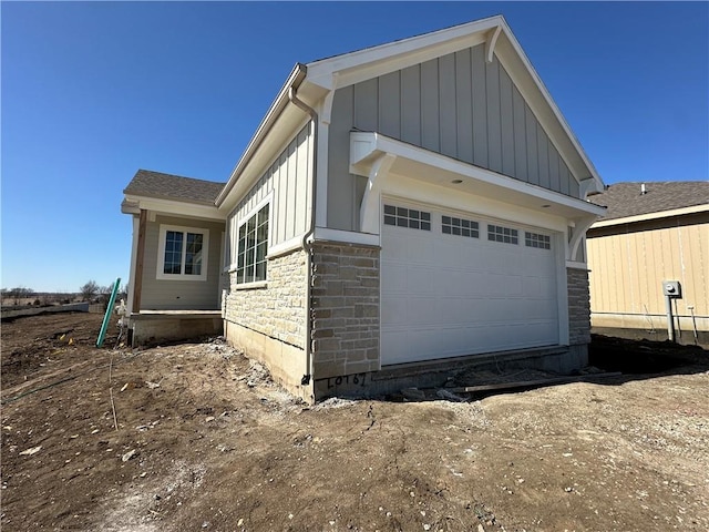 view of side of property featuring stone siding, board and batten siding, and an attached garage