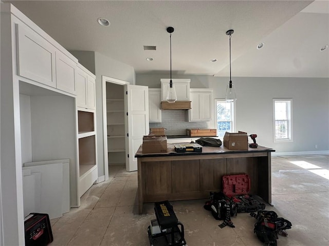 kitchen with visible vents, decorative backsplash, white cabinetry, dark countertops, and a center island