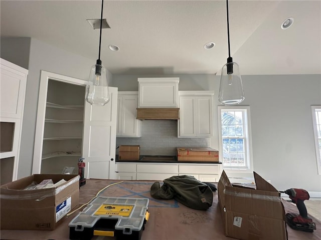 kitchen with custom range hood, backsplash, and white cabinetry