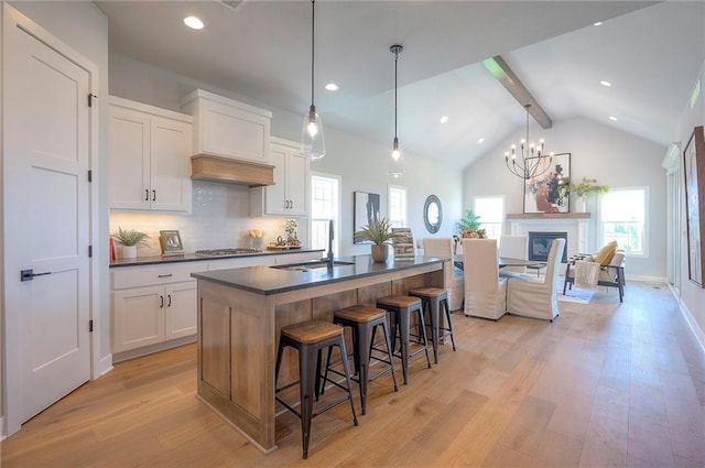 17372 S Kaw St, Olathe, KS 66062 - kitchen featuring dark countertops, beamed ceiling, light wood-style floors, white cabinetry, and a kitchen breakfast bar