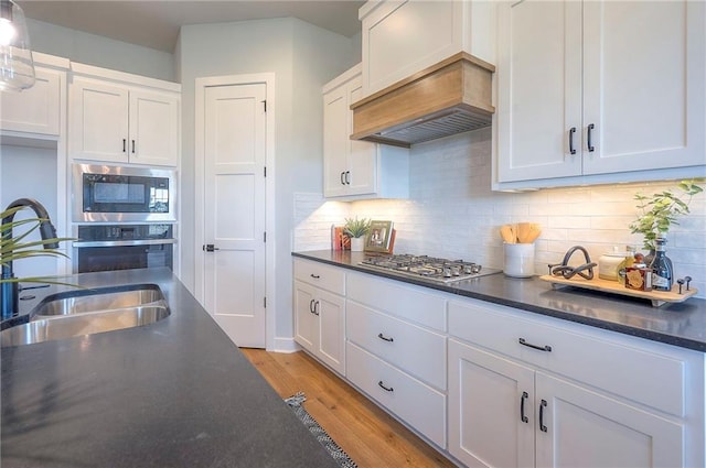 17372 S Kaw St, Olathe, KS 66062 - kitchen featuring stainless steel appliances, a sink, white cabinets, light wood-style flooring, and tasteful backsplash