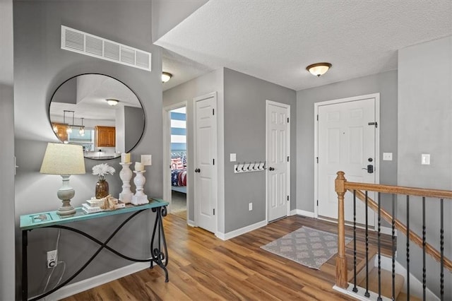 entrance foyer featuring visible vents, light wood-style flooring, baseboards, and a textured ceiling