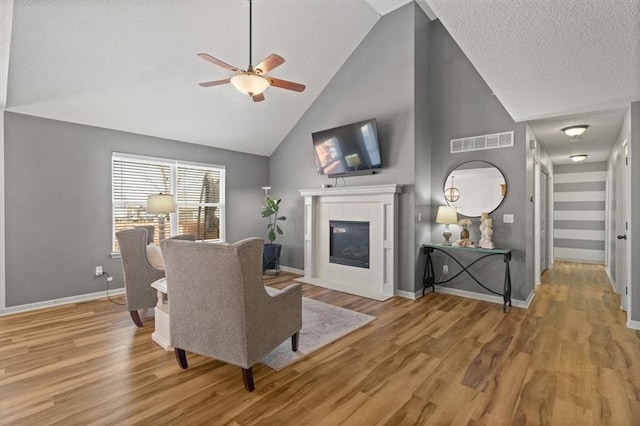 living room with a ceiling fan, visible vents, a fireplace, and light wood-style flooring