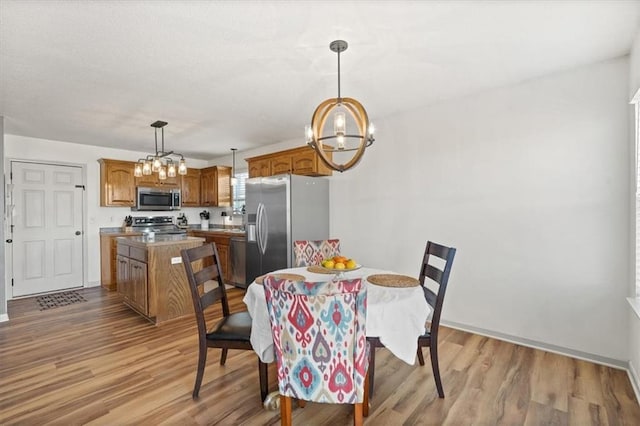 dining area with light wood-style floors, a notable chandelier, and baseboards