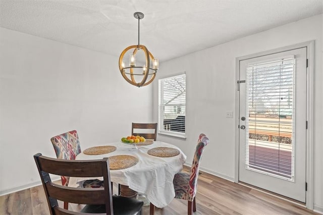 dining space featuring a chandelier, baseboards, and light wood finished floors