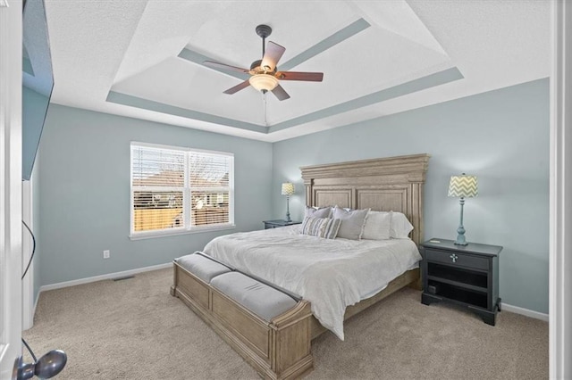 bedroom with light carpet, visible vents, baseboards, a raised ceiling, and a ceiling fan