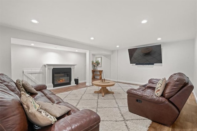 living area featuring light wood-type flooring, a glass covered fireplace, baseboards, and recessed lighting