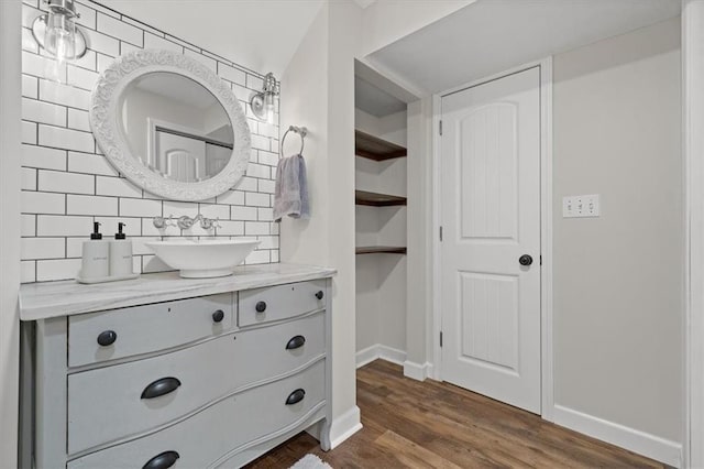 bathroom with wood finished floors, backsplash, vanity, and baseboards