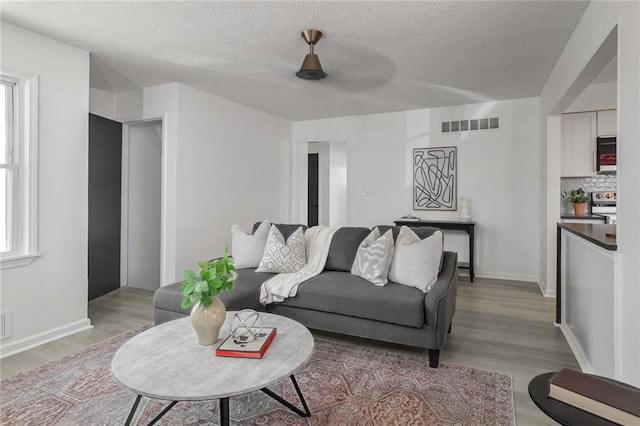 living room with visible vents, light wood-style flooring, and baseboards