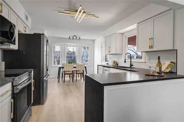 kitchen with appliances with stainless steel finishes, dark countertops, white cabinets, and a sink