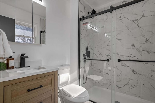 bathroom with toilet, a marble finish shower, and vanity