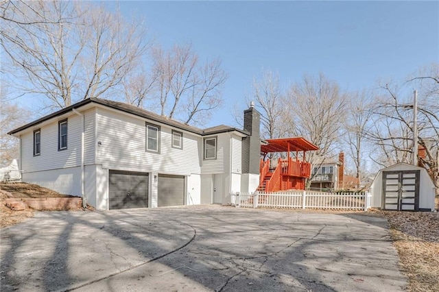 view of side of property featuring aphalt driveway, a chimney, fence, a garage, and stairs