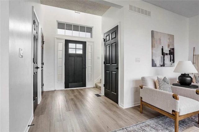 entryway featuring light wood finished floors, baseboards, and visible vents