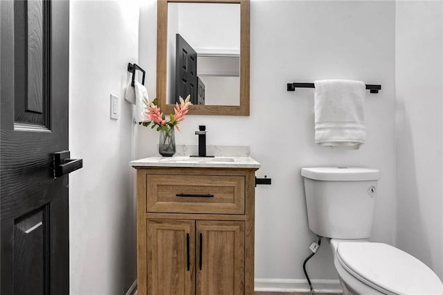 bathroom with baseboards, vanity, and toilet