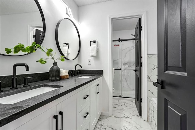 bathroom with double vanity, marble finish floor, a marble finish shower, and a sink