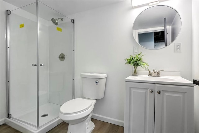 bathroom featuring toilet, a shower stall, vanity, wood finished floors, and baseboards