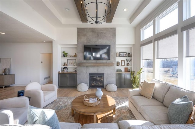 living area with a tile fireplace, light wood-style flooring, and an inviting chandelier