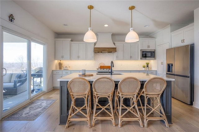 kitchen featuring stainless steel appliances, tasteful backsplash, light countertops, custom range hood, and a sink