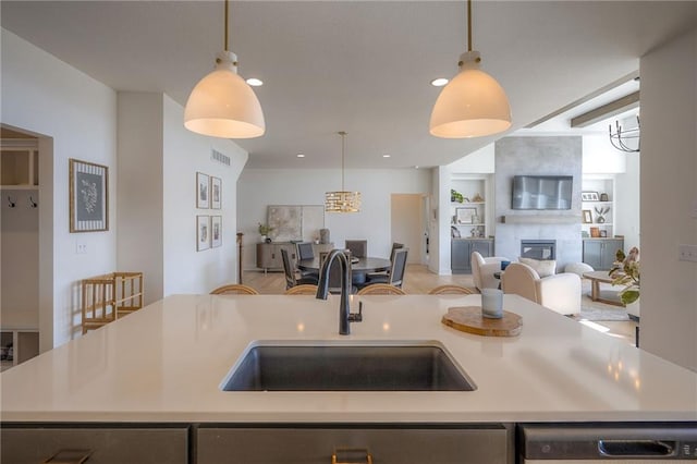 kitchen with a large fireplace, dishwasher, open floor plan, light countertops, and a sink