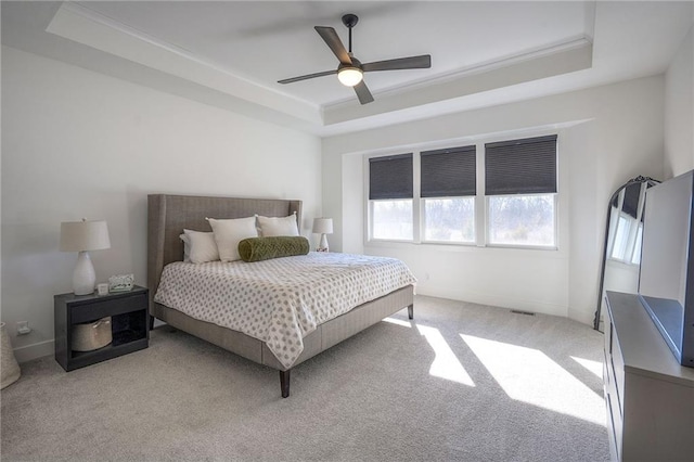 bedroom with ceiling fan, light colored carpet, baseboards, ornamental molding, and a raised ceiling