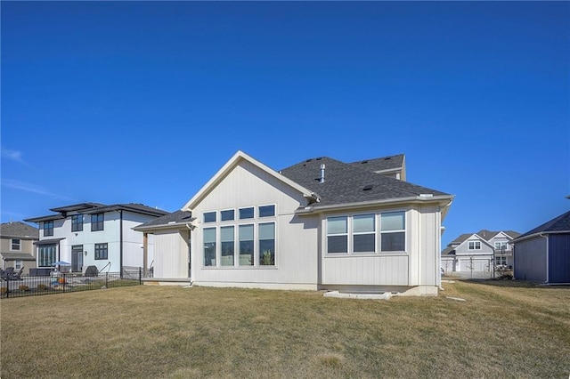 back of property with a residential view, fence, a lawn, and roof with shingles