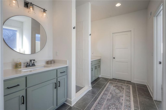 full bath with tile patterned floors, a tile shower, vanity, and baseboards