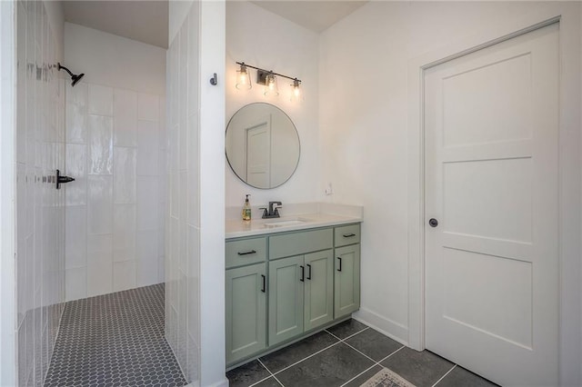 bathroom featuring tile patterned flooring, a tile shower, vanity, and baseboards