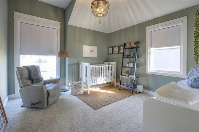 carpeted bedroom with a crib and baseboards