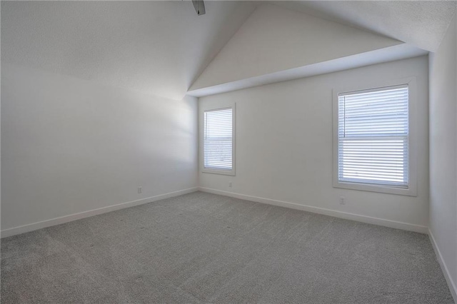 carpeted empty room with lofted ceiling, a textured ceiling, and baseboards