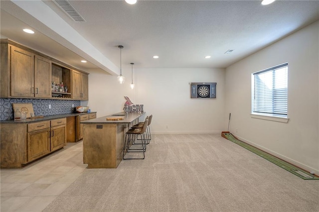 bar featuring baseboards, visible vents, decorative backsplash, light colored carpet, and hanging light fixtures