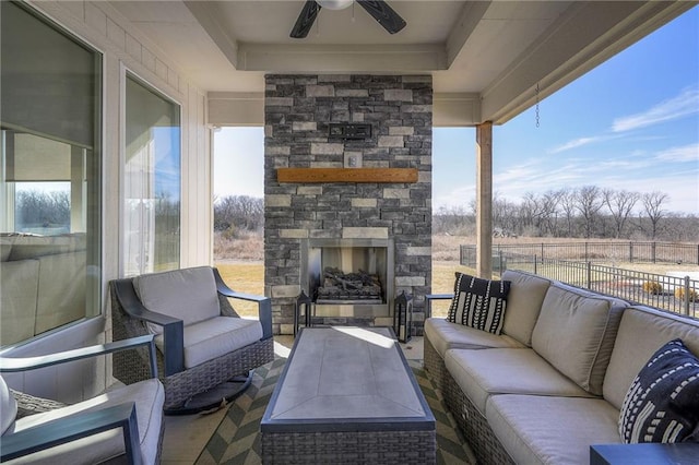 view of patio / terrace featuring ceiling fan, an outdoor living space with a fireplace, and fence