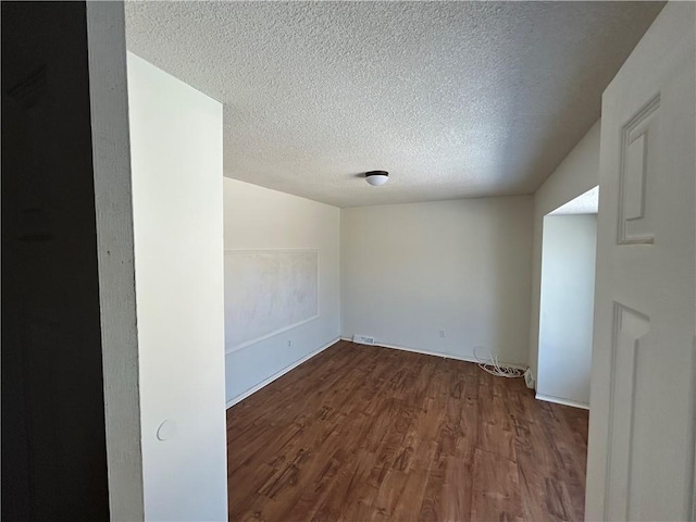 empty room with a textured ceiling and wood finished floors