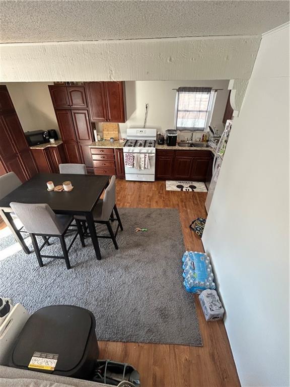 kitchen with dark wood-style floors, a textured ceiling, gas stove, and a sink