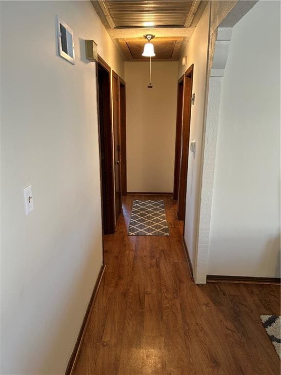 corridor featuring attic access, visible vents, baseboards, and wood finished floors