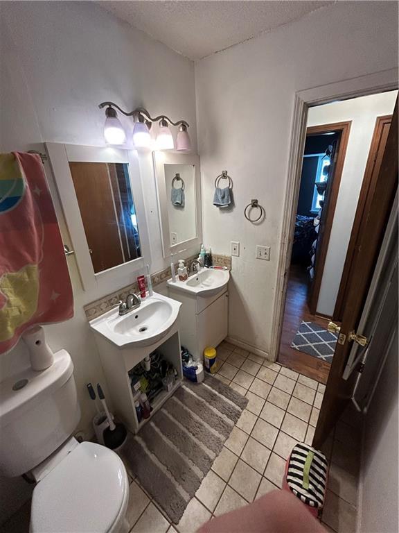 bathroom featuring a textured ceiling, a sink, toilet, and tile patterned floors