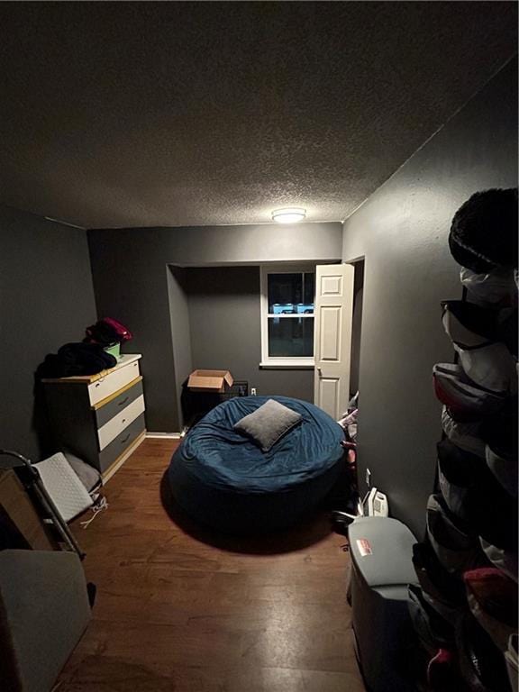 bedroom with a textured ceiling and wood finished floors