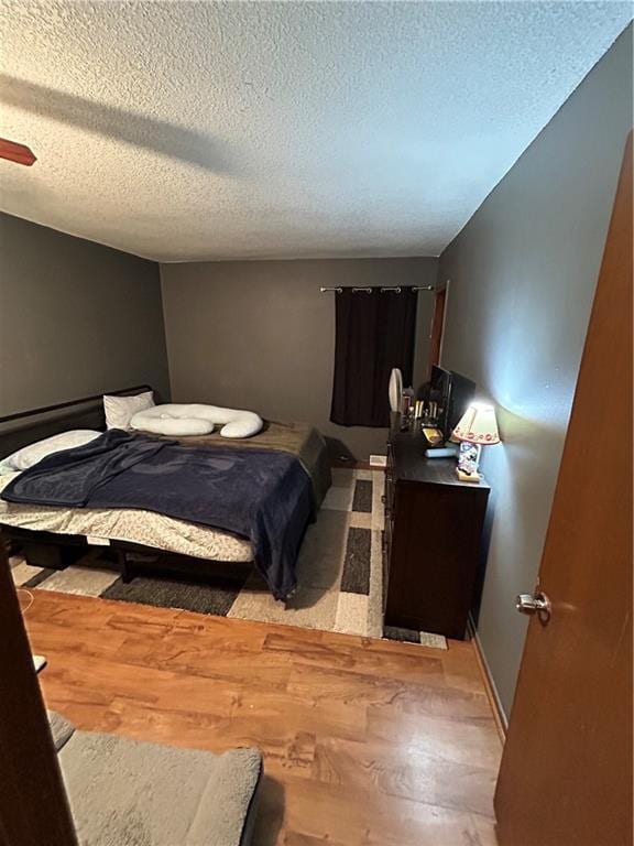 bedroom with a textured ceiling, wood finished floors, a ceiling fan, and baseboards