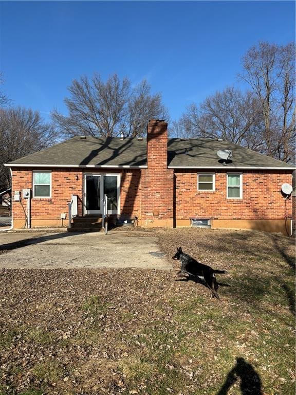 rear view of house with brick siding and a chimney