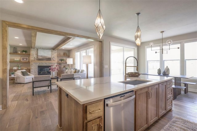 12604 W 170th St, Overland Park, KS 66221 - kitchen with stainless steel dishwasher, wood finished floors, a fireplace, a center island with sink, and pendant lighting