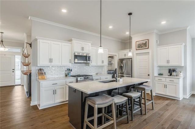 kitchen with dark wood-style floors, appliances with stainless steel finishes, a breakfast bar, white cabinetry, and a sink