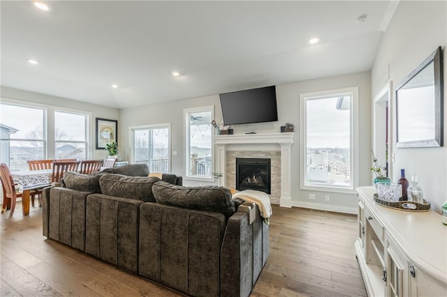 living room with recessed lighting, baseboards, hardwood / wood-style floors, and a tile fireplace