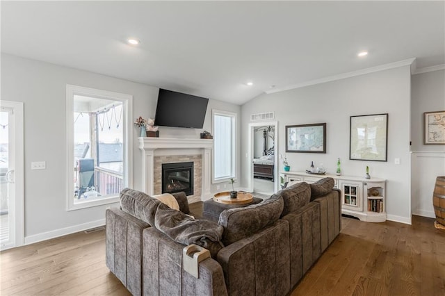 living room featuring baseboards, visible vents, wood finished floors, and a glass covered fireplace