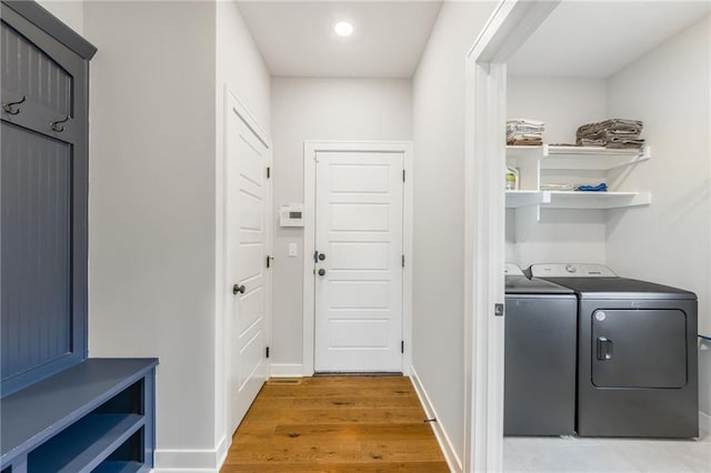 laundry area featuring baseboards, laundry area, washing machine and dryer, and light wood-style floors