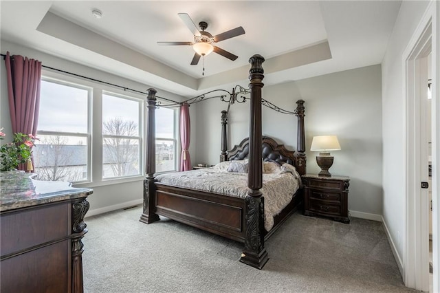 bedroom with light carpet, baseboards, and a tray ceiling